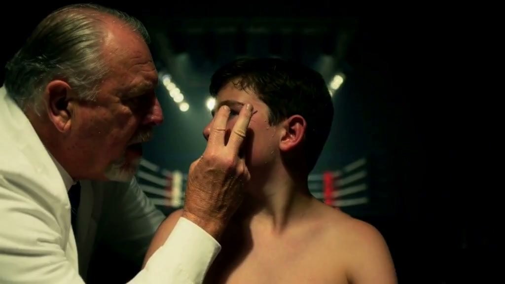 The exact frame: the cutman holds two fingers to the boy's eye